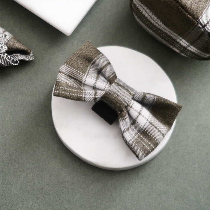 Olive check bow tie with black center band, displayed on a white circular coaster.