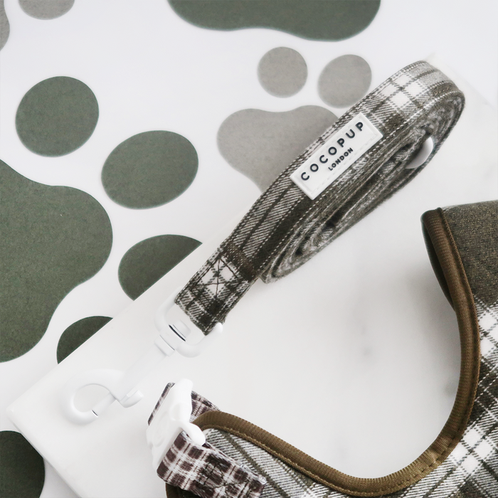 Olive check dog lead by Cocopup London with padded handle, displayed on a paw-print pattern surface.
