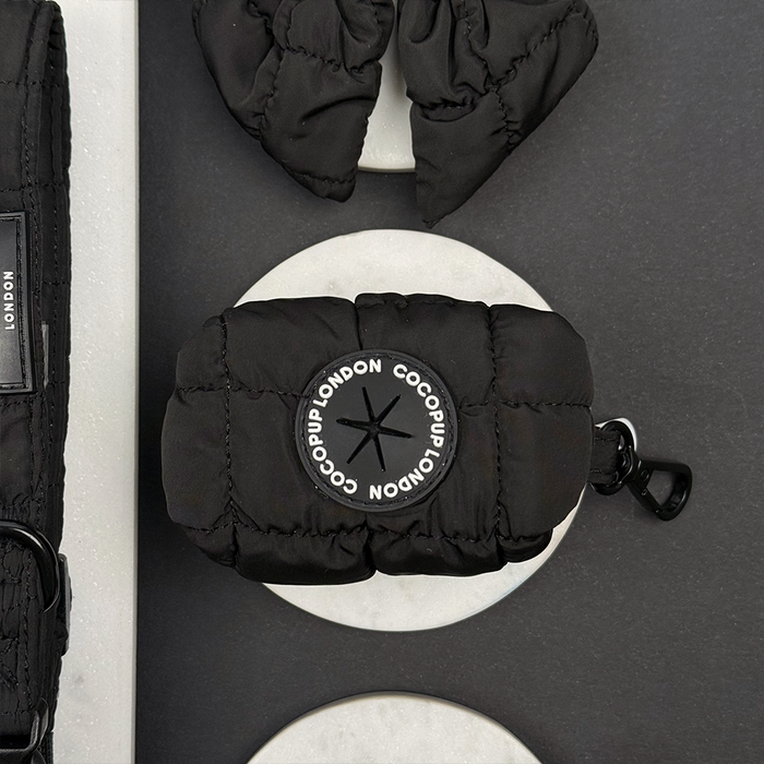 Black quilted Cocopup London poop bag holder with matching grey dog walking accessories on a grey background.