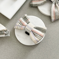 Plaid bow tie with red and navy pattern by Cocopup London displayed on a white marble coaster against a light grey background.