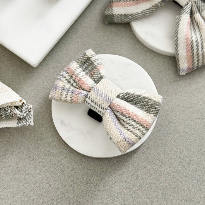 Plaid bow tie with red and navy pattern by Cocopup London displayed on a white marble coaster against a light grey background.