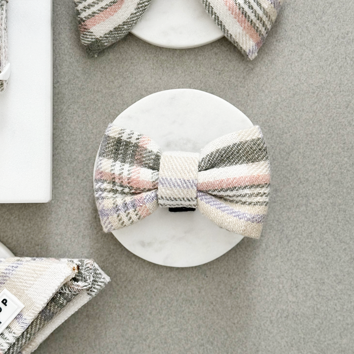 Oxford plaid dog bow tie by Cocopup London on white marble, surrounded by other partially visible bow ties.