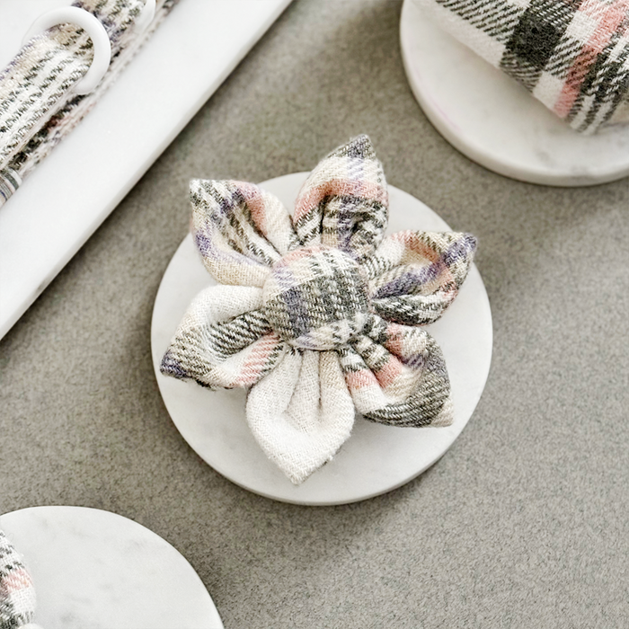 Pastel plaid fabric collar flower from Cocopup London, displayed on a white marble round base, top view.