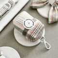 Oxford plaid poop bag holder with white clip by Cocopup London on a marble coaster.
