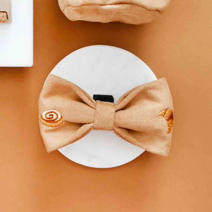 Cocopup London Pawtisserie Bow Tie with cream embroidered swirls and crescents on a white display, brown background.