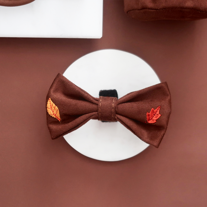 Pawtumn Leaves Bow Tie with orange leaf embroidery, displayed on a white surface with a brown background.