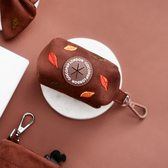 Brown velvet poop bag holder with embroidered leaves and attached carabiner.