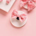 Pink lace Cocopup London dog bow tie on a white round dish with marble and pink accents in the background.