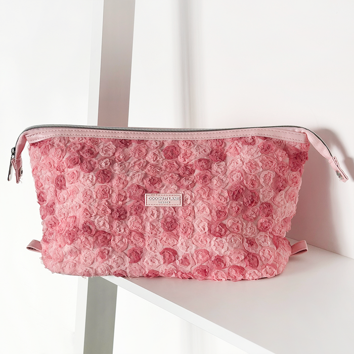 Pink Peony Pup expandable makeup bag with floral pattern on a white shelf against a white background.