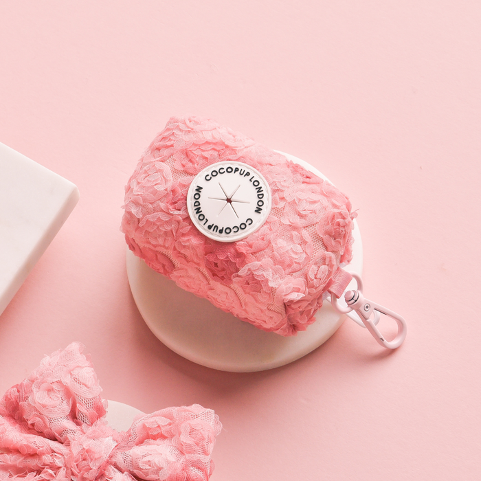 Pink floral Peony Pup poop bag holder by Cocopup London next to a matching pink lace bow.