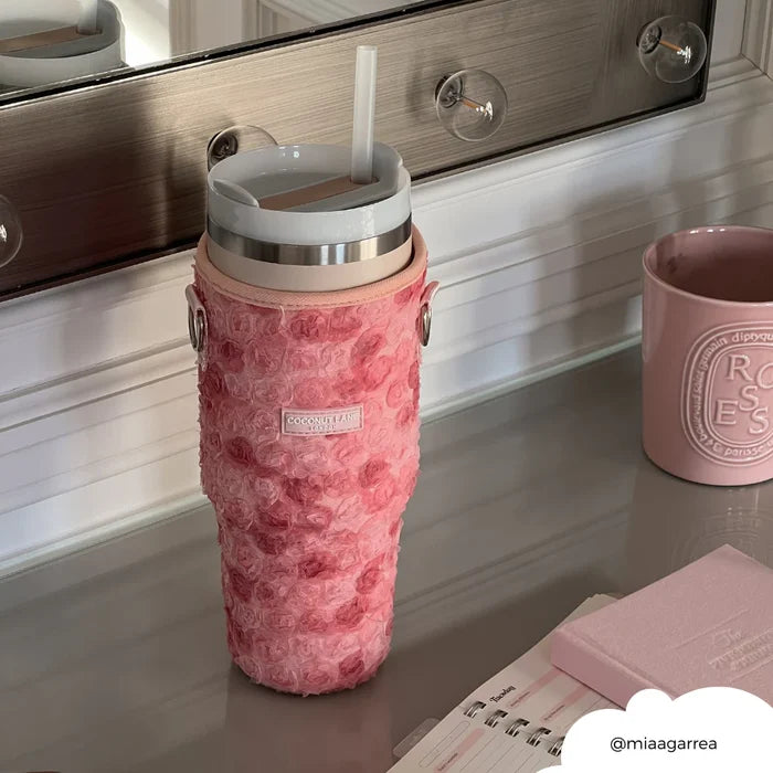 Pink floral tumbler carry case with gold zipper on a vanity, next to a pink mug and notebook.