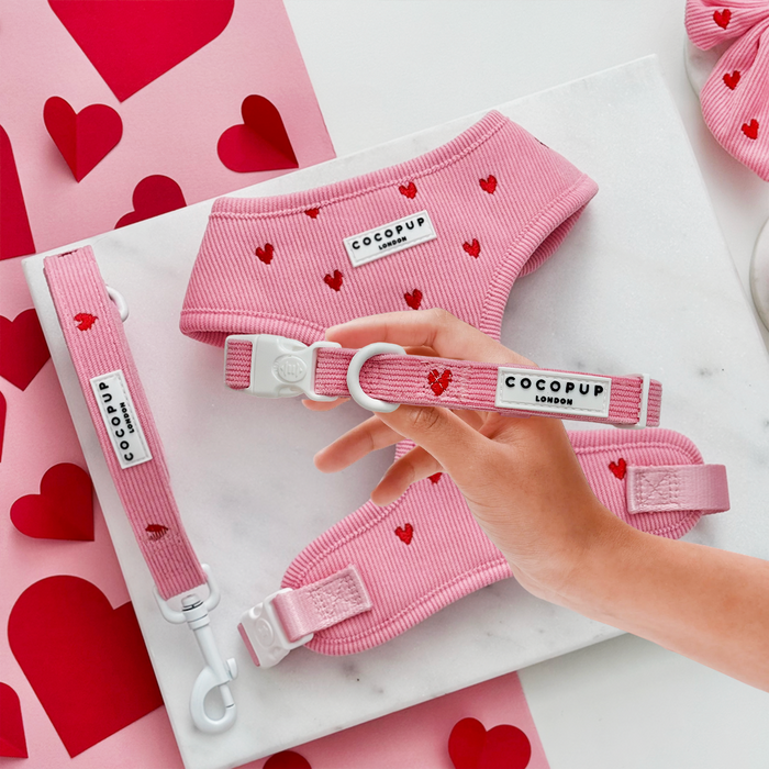 Pink Heartstrings cord harness, lead and collar set by Cocopup London on a marble tray, strap held by a hand.