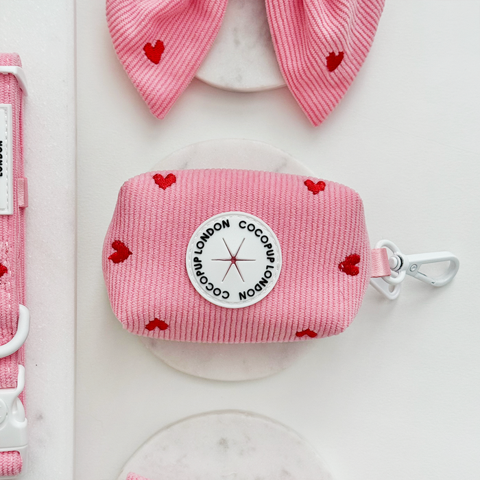 Pink cord poop bag holder with red heart pattern from Cocopup London on a white background.