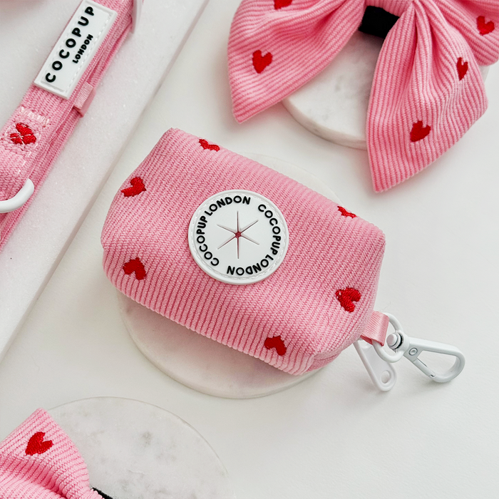 Pink cord poop bag holder with red heart pattern and compact shape from Cocopup London.