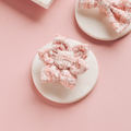 Pink textured tweed collar flower and matching bow clip from Cocopup London on pink and white backgrounds.