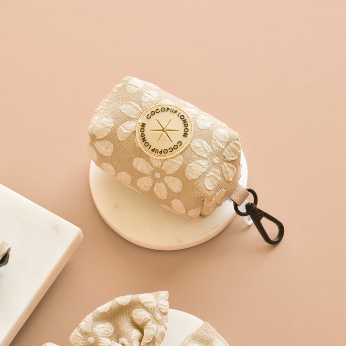 Beige Cocopup London Luxe poop bag holder with floral pattern and metal clip against a neutral background.