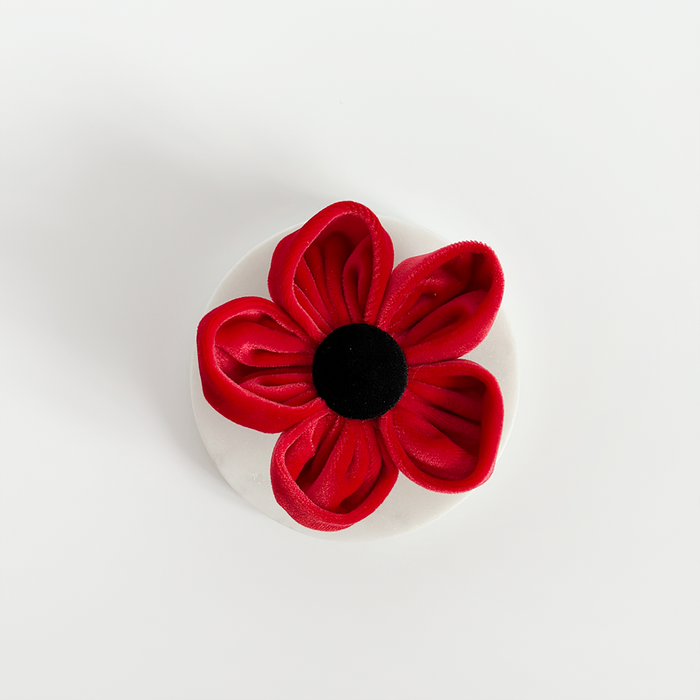 Red fabric flower dog collar accessory with a black center, designed to resemble a poppy.