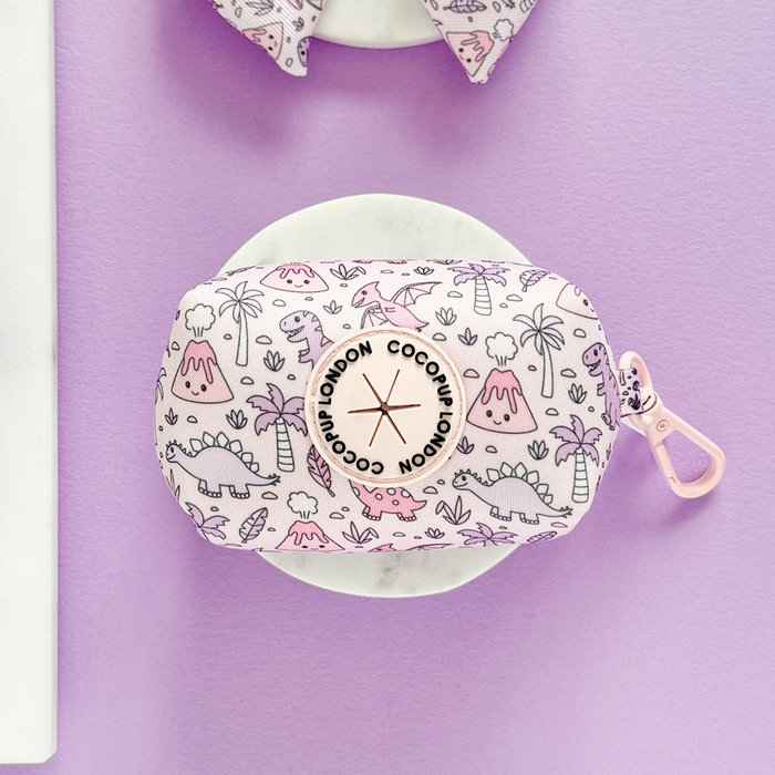 Pastel pink poop bag holder with volcano pattern and pink clip, displayed on a lavender background.