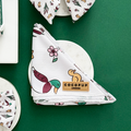 Folded Cocopup London bandana with duck and floral print, displayed on a marble coaster against a green background.