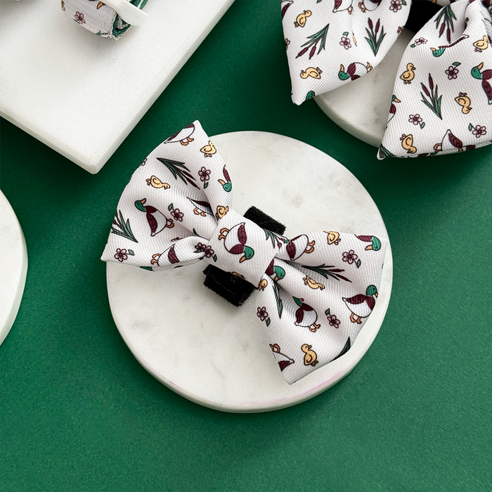 Puddle Pup Bow Tie by Cocopup London with a mushroom and leaf print, displayed on a round marble surface.