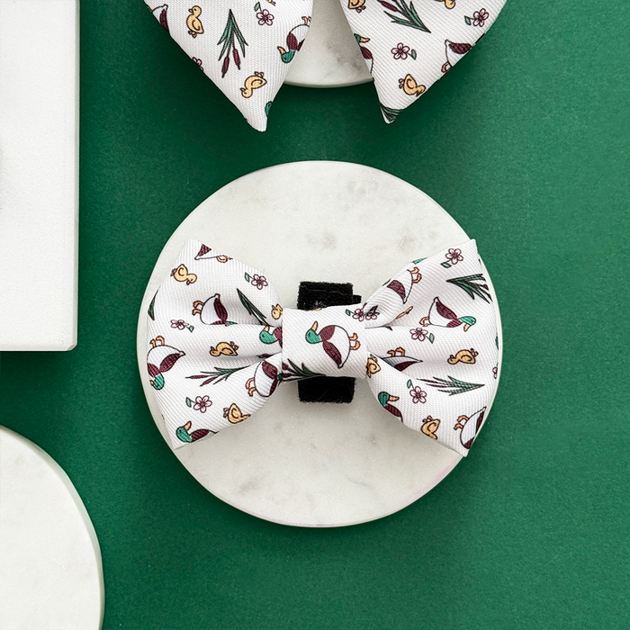 Cocopup London Puddle Pup bow tie with a colorful mushrooms, flowers, and leaves print on a white background.