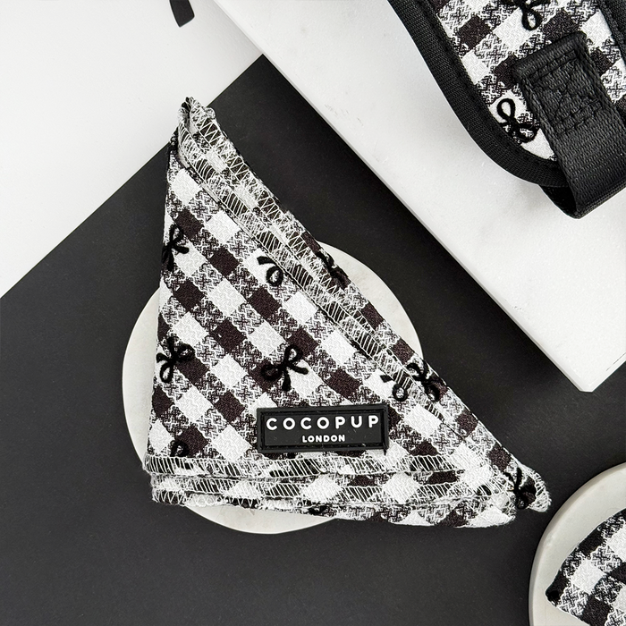 Black and white check Pup in Paris Bandana by Cocopup London displayed on a round white dish.