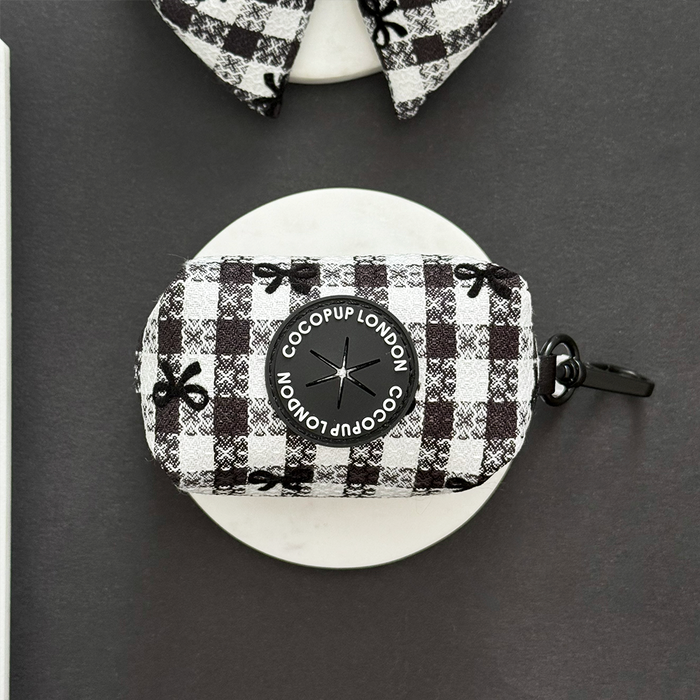 Black and white plaid poop bag holder with logo on round surface.