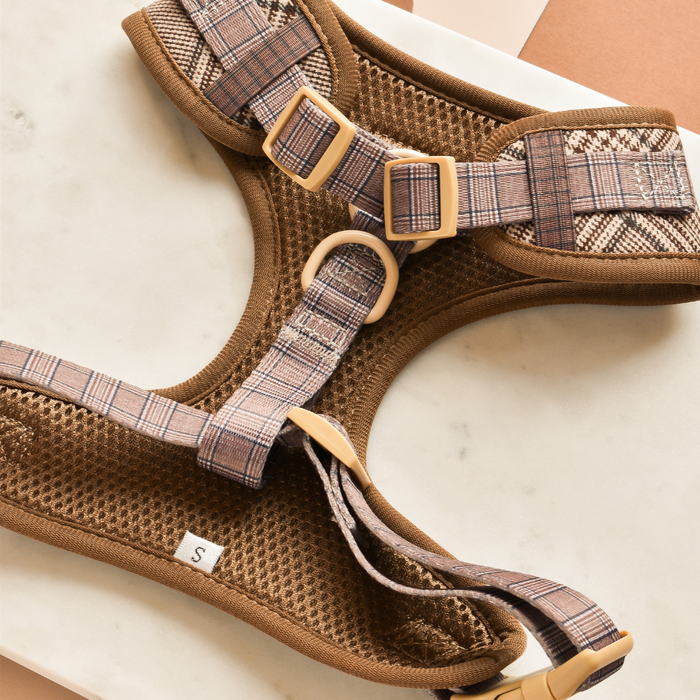 Brown and beige plaid adjustable dog harness on a marble surface.
