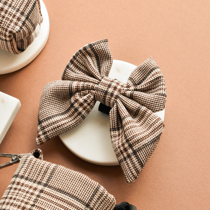 Brown and beige plaid Cocopup London Pup Sailor Bow Tie displayed on a white dish against a tan background.