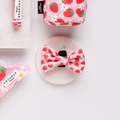 White bow tie, bandana, and pouch set with red strawberry pattern from Cocopup London displayed on white background.