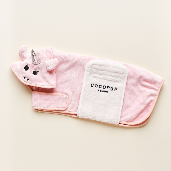 Introducing the PRE-ORDER Pupicorn Drying Robe from Cocopup London — a pink dog jacket designed to resemble a unicorn. This unicorn-inspired robe features a hood with a unicorn horn and ears, and it includes a white belly strap printed with the brand "COCOPUP LONDON." Made from premium microfibre, it is displayed on a light-colored background.