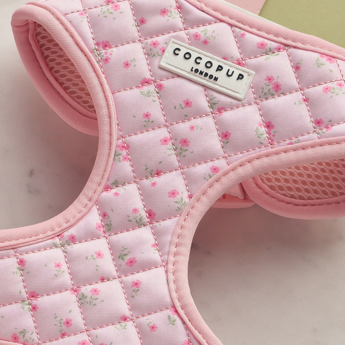 Pink quilted harness with ditsy floral pattern and adjustable neck, by Cocopup London, on a light surface.