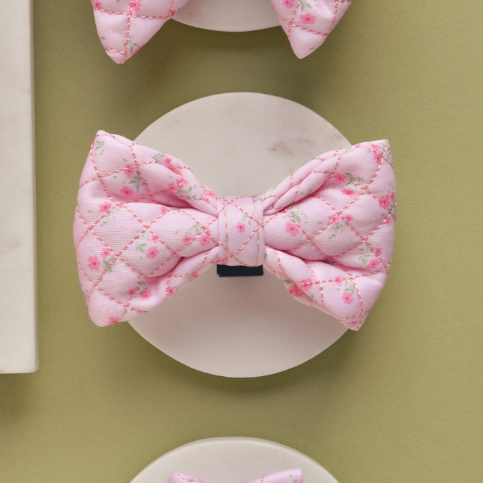 Pink quilted bow tie with ditsy floral pattern by Cocopup London, displayed on a white stand.