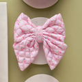 Quilted pink sailor bow tie with a ditsy floral pattern from Cocopup London, displayed on a pale round surface.