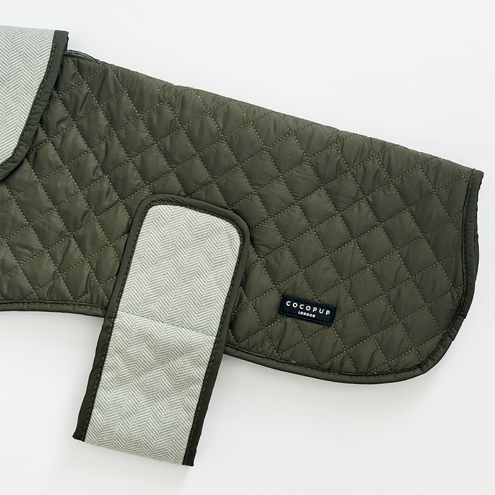 Olive green quilted dog coat with water resistant finish, herringbone straps, and a small black Cocopup London label.