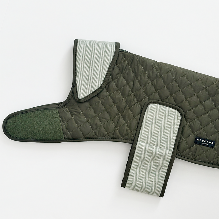 Quilted khaki dog coat with gray trim and Velcro closures, laid flat on a white background.