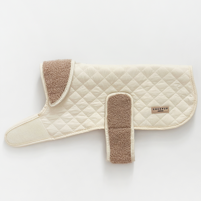 Creamy chai quilted dog coat with teddy lining and velcro straps, laid flat on a white background.