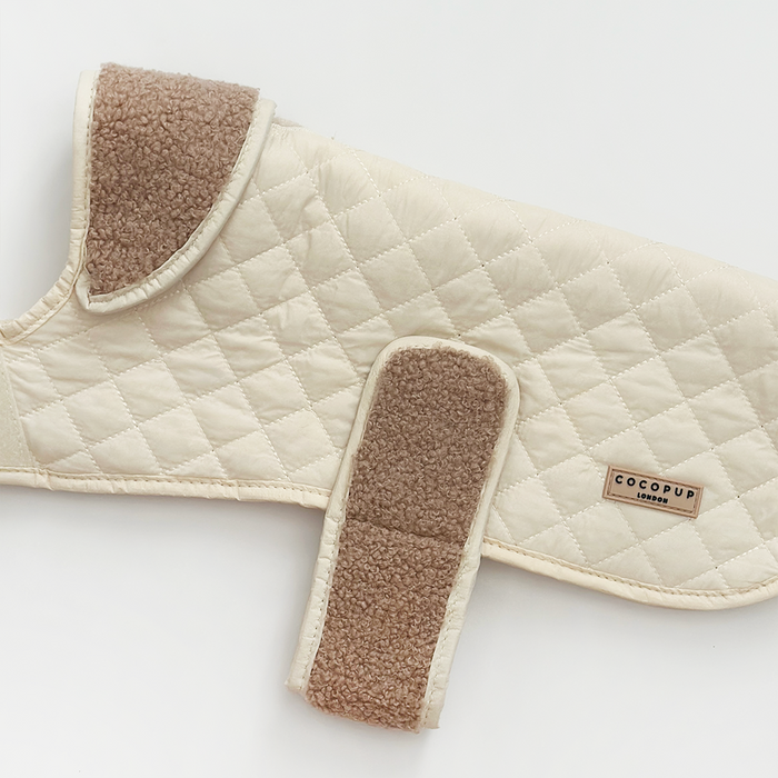Cream-colored quilted dog coat with brown fleece lining and soft teddy-style texture by Cocopup London.
