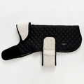 Midnight black quilted dog coat with white fleece lining, Velcro straps, and a side logo tag.