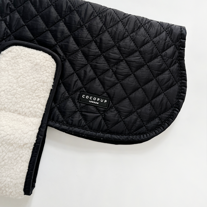 Black quilted dog coat with white fleece lining and Cocopup London branded label.