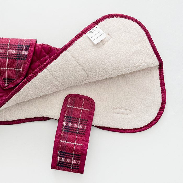 Mulberry plaid quilted dog coat with cream sherpa lining and velcro strap, shown flat.