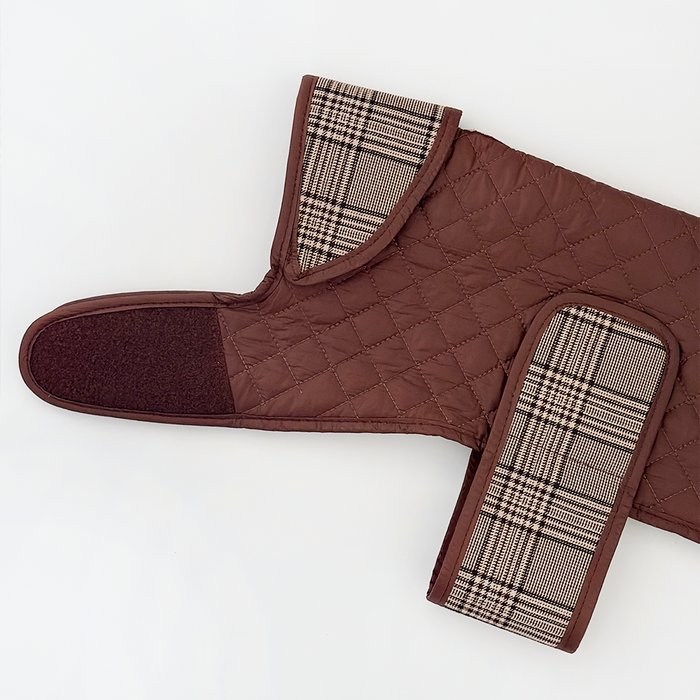 Quilted dog coat in pup plaid with teddy lining and Velcro straps, laid flat on a white background.