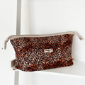 Quilted makeup bag with leopard print by Cocopup London, displayed on a white shelf next to a Coconut Lane label.