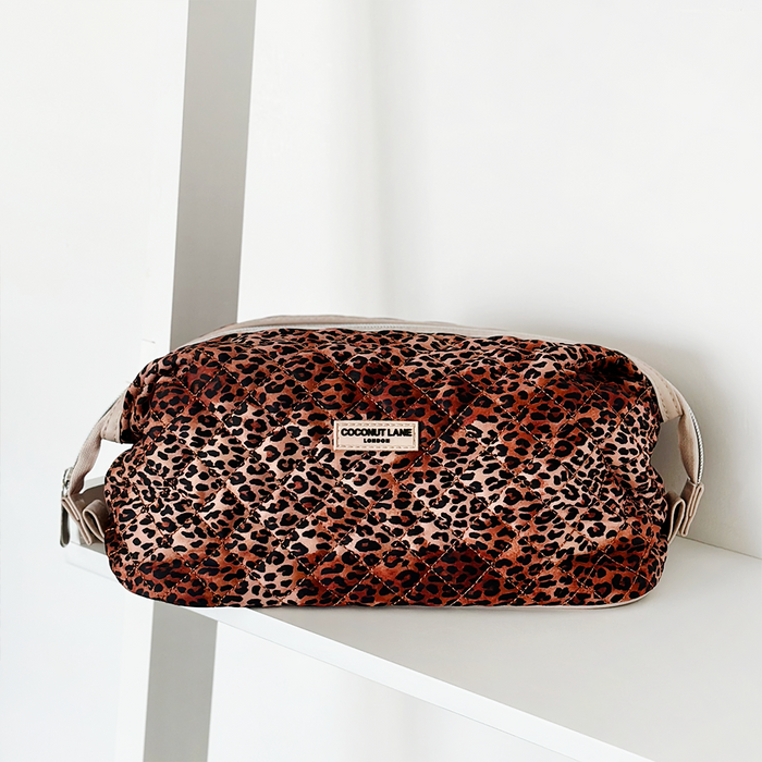 Quilted leopard print expandable makeup bag with Cocopup London label on a white shelf.