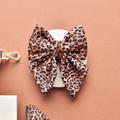 Quilted leopard print sailor bow tie by Cocopup London on a white plate, brown background.