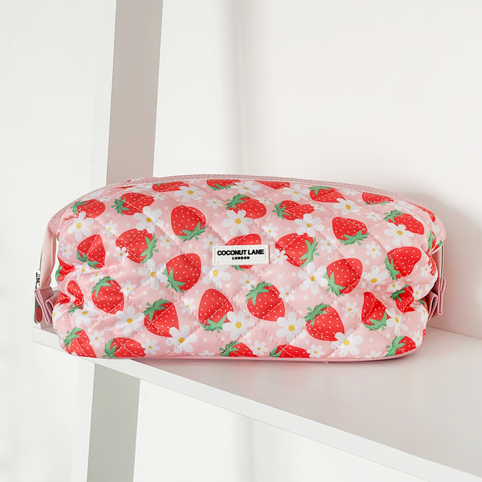 Pink quilted makeup bag with Pupberry Fields pattern by Cocopup London on a white shelf.