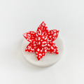 Red and pink leopard print five-petaled dog collar flower on a white round surface, white background.