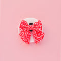 Red and pink leopard print sailor bow tie on a round white display, set against a pink background.
