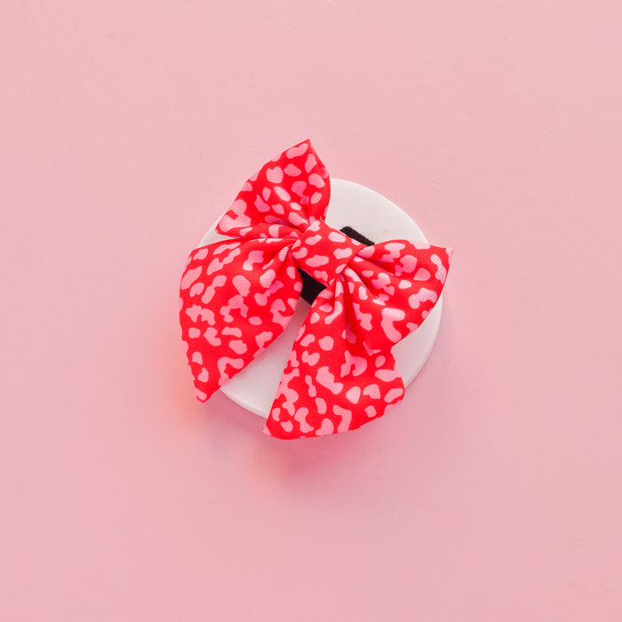 Red and pink leopard print sailor bow tie on a dish, set against a pink background.