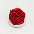 Red rose-shaped dog collar flower by Cocopup London on a white marble coaster, set against a plain white background.